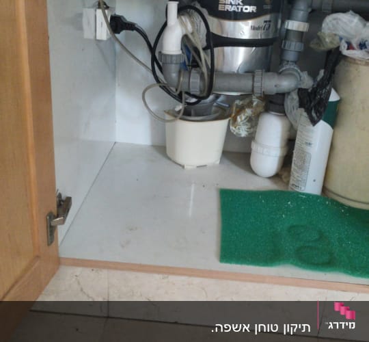 כיור עם מערכת סינון מים וצנרת מתחת לארון